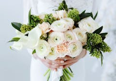 A soft arrangement of white, pink and green flowers, held by an expectant bride