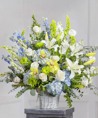 Blue & White Garden Sympathy Basket featuring hydrangea, delphinium, roses, stock and lush foliage