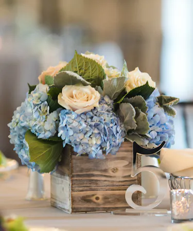 Blue and White Garden Table Centerpiece featuring blue hydrangea, white roses and dusty miller