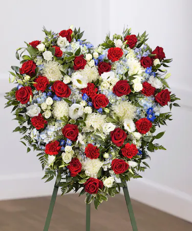 Patriot Heart Sympathy Flower Arrangement featuring red, white and blue flowers including roses, hydrangea and delphinium on a standing easel