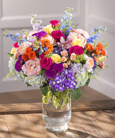 Spring Lush Garden Vase Arrangement featuring hydrangea, roses, delphinium, stock and English roses in a glass hurricane vase