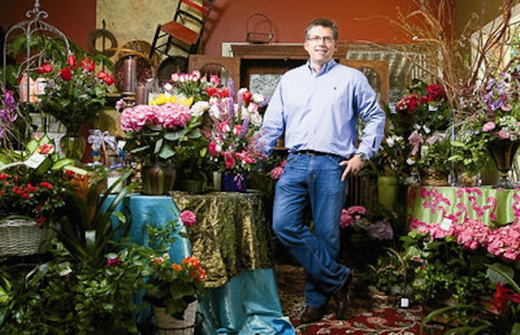 Surrounded by flowers and plants alike, Charles Carithers poses in his showroom