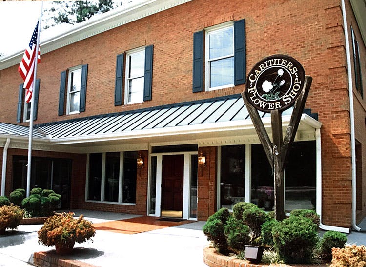 An exterior view of our Marietta location, featuring our wooden sign and an American flag