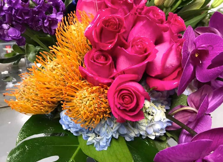 A bouquet of pink roses, paired with orange, purple and pale blue accents